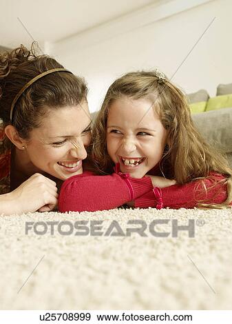 Stock Photo - Mother and daughter lying on rug. Fotosearch