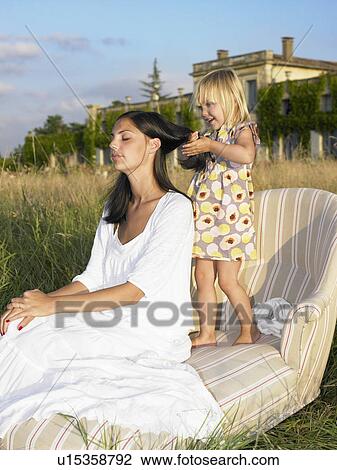 Stock Image - Mother and daughter on sofa in a field. Fotosearch