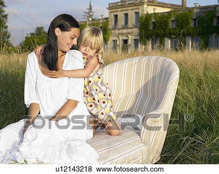 Stock Photo - Mother and daughter on sofa in a field. Fotosearch