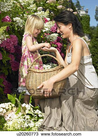Stock Image - Mother and daughter plucking flowers. Fotosearch