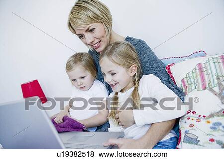 Stock Photo - Mother and two girls looking at laptop. Fotosearch