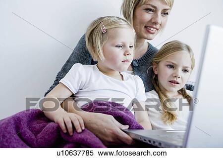 Stock Photography - Mother and two girls looking at laptop. Fotosearch