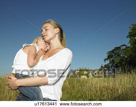 Stock Image - Mother carrying her sleeping daughter. Fotosearch