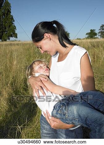 Stock Image - Mother carrying her sleeping daughter. Fotosearch