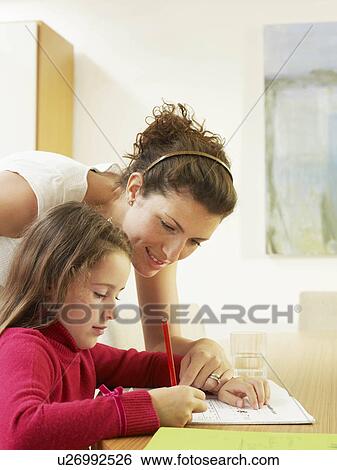 Stock Photograph - Mother helping daughter with homework. Fotosearch
