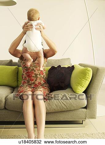 Stock Image - "Mother holding up baby, faces hidden". Fotosearch