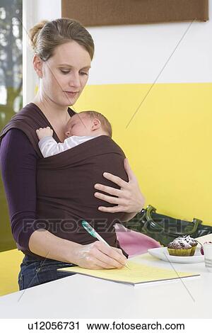 "Mother with baby in baby sling, writing" View Large Photo Image Stock Image - "Mother with baby in baby sling, writing". Fotosearch