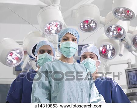 Stock Image - Nurses and female surgeon in theatre. Fotosearch