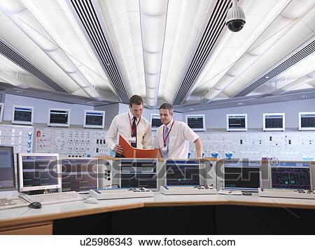 Stock Image - Operators talking in control room. Fotosearch