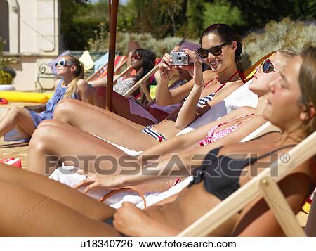 Stock Photograph - People enjoying summer around the pool. Fotosearch