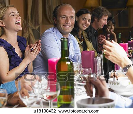 Stock Image - People laughing at dinner table. Fotosearch