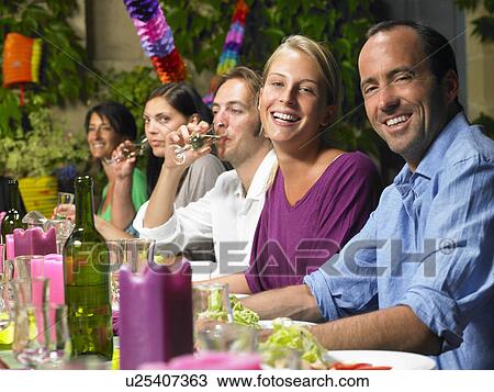 Stock Image - "People sitting at table, celebrating". Fotosearch