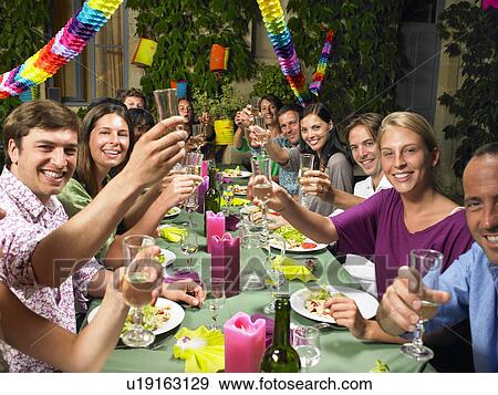 Stock Photo - "People sitting at table, celebrating". Fotosearch