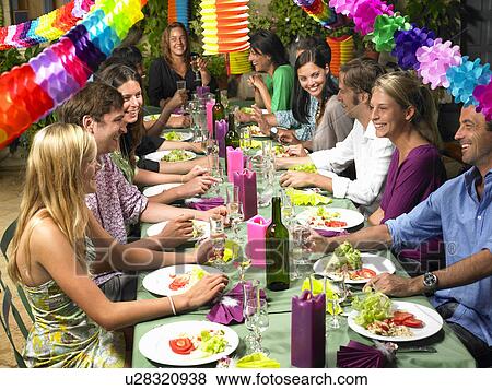 Stock Photo - "People sitting at table, celebrating". Fotosearch