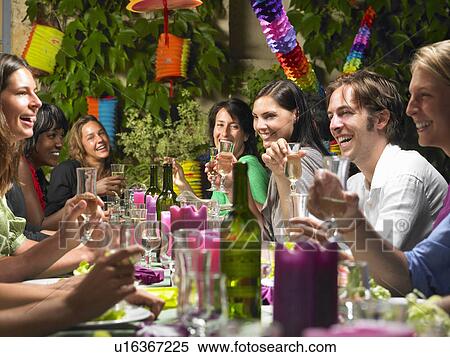 Stock Photography - "People sitting at table, celebrating". Fotosearch