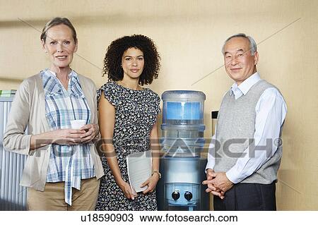 Portrait of co-workers by water cooler View Large Photo Image Stock Image - Portrait of co-workers by water cooler. Fotosearch