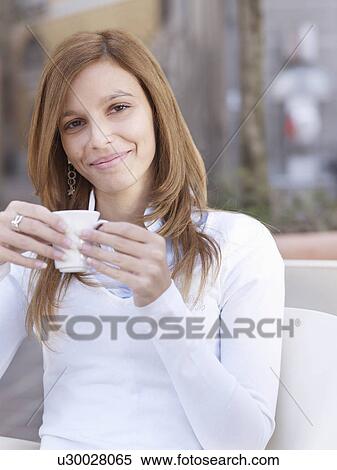Portrait of young woman holding a coffee View Large Photo Image Stock Photography - Portrait of young woman holding a coffee. Fotosearch