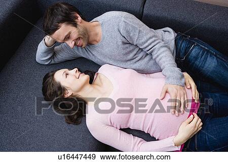 Pregnant woman and man laying on couch View Large Photo Image Stock Photo - Pregnant woman and man laying on couch. Fotosearch