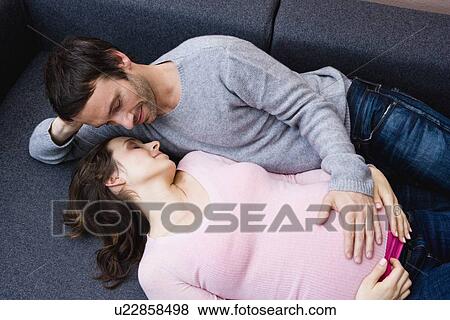 Pregnant woman and man laying on couch View Large Photo Image Stock Photo - Pregnant woman and man laying on couch. Fotosearch