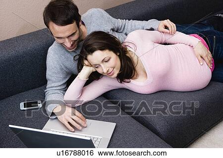 Pregnant woman and man laying on couch View Large Photo Image Stock Photograph - Pregnant woman and man laying on couch. Fotosearch