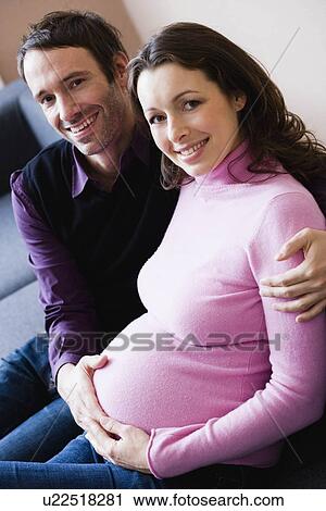 Pregnant woman and man sitting on couch View Large Photo Image Stock Image - Pregnant woman and man sitting on couch. Fotosearch