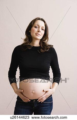 Stock Image - Pregnant woman holding her belly. Fotosearch