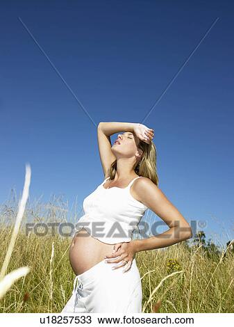 Stock Image - Pregnant woman in a field. Fotosearch
