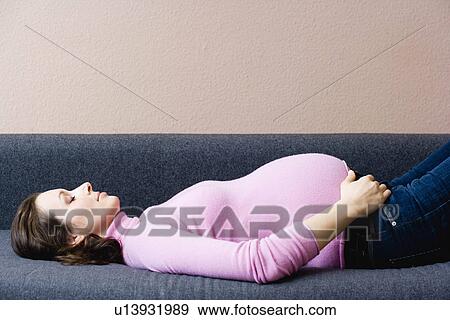 Stock Photo - Pregnant woman laying on couch. Fotosearch