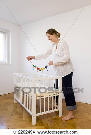 Picture - Pregnant woman looking at mobile toy. Fotosearch