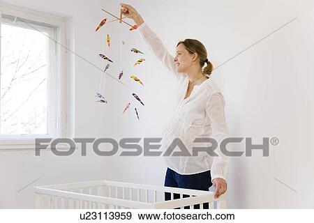 Stock Photo - Pregnant woman looking at mobile toy. Fotosearch
