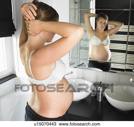 Pregnant woman looking in mirror View Large Photo Image Stock Image - Pregnant woman looking in mirror. Fotosearch