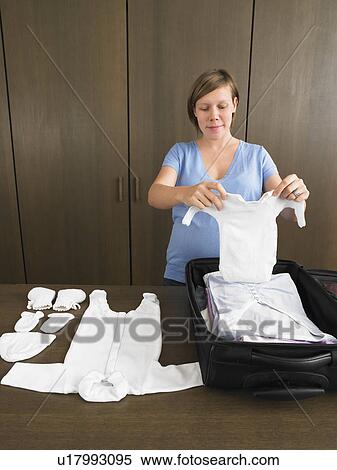 Stock Photography - Pregnant woman packing maternity bag. Fotosearch