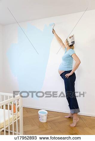 Stock Image - Pregnant woman painting nursery. Fotosearch