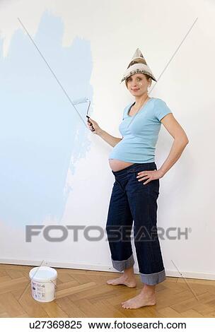 Stock Photography - Pregnant woman painting nursery. Fotosearch