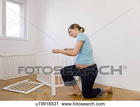 Pregnant woman putting together baby bed View Large Photo Image Stock Image - Pregnant woman putting together baby bed. Fotosearch