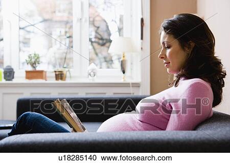 Stock Image - Pregnant woman reading a book. Fotosearch
