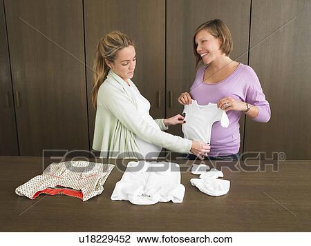 Pregnant women looking at baby clothes View Large Photo Image Stock Image - Pregnant women looking at baby clothes. Fotosearch