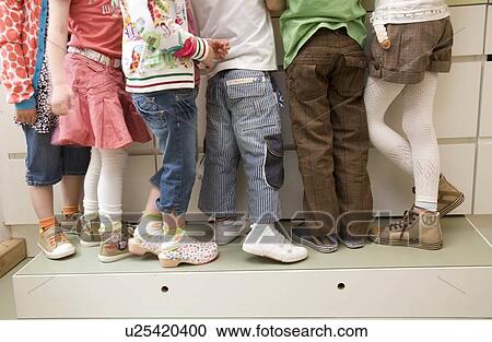 Stock Image - Six pair of girls and boys legs. Fotosearch