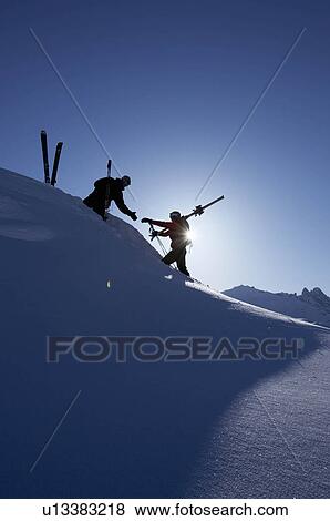 Skiers helping each other on mountain View Large Photo Image Stock Photo - Skiers helping each other on mountain. Fotosearch