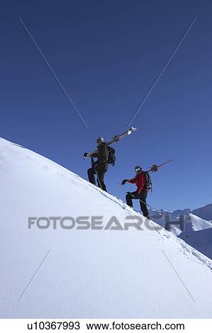 Skiers walking on side of mountain View Large Photo Image Stock Image - Skiers walking on side of mountain. Fotosearch