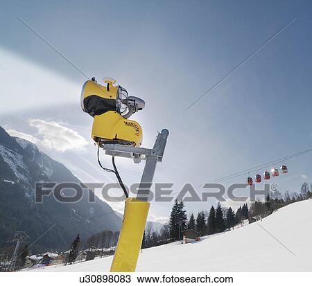 Stock Image - Snowblower and cable car in ski resort. Fotosearch