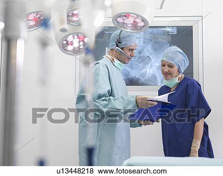 Stock Photo - Surgeon and nurse discussing notes. Fotosearch