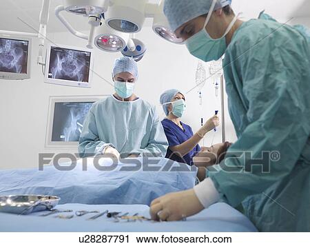 Stock Image - Surgeon and nurses performing surgery. Fotosearch