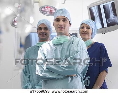 Stock Image - Surgeons and nurse in operating theatre. Fotosearch