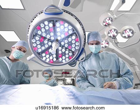 Stock Photograph - Surgeons operating in theatre. Fotosearch