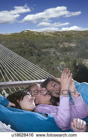 Stock Photograph - Teen girls laugh with phone outside. Fotosearch