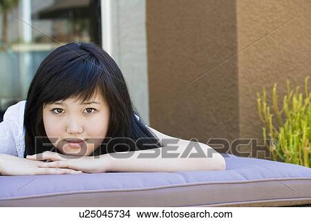 Picture - Teen relaxing on lounge chair outside. Fotosearch
