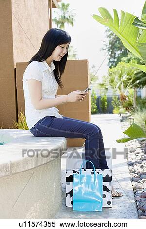 Teen with shopping bags text messaging View Large Photo Image Stock Photography - Teen with shopping bags text messaging. Fotosearch