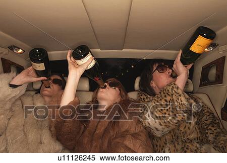 Stock Photography - Three women drinking champagne in car. Fotosearch