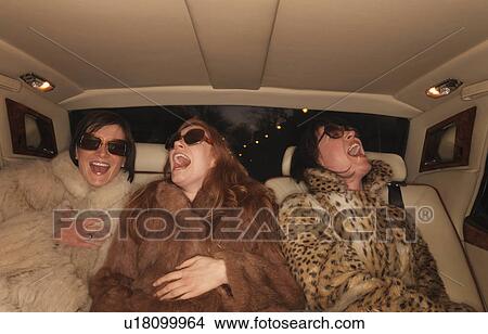 Picture - Three women on backseat of luxury car. Fotosearch